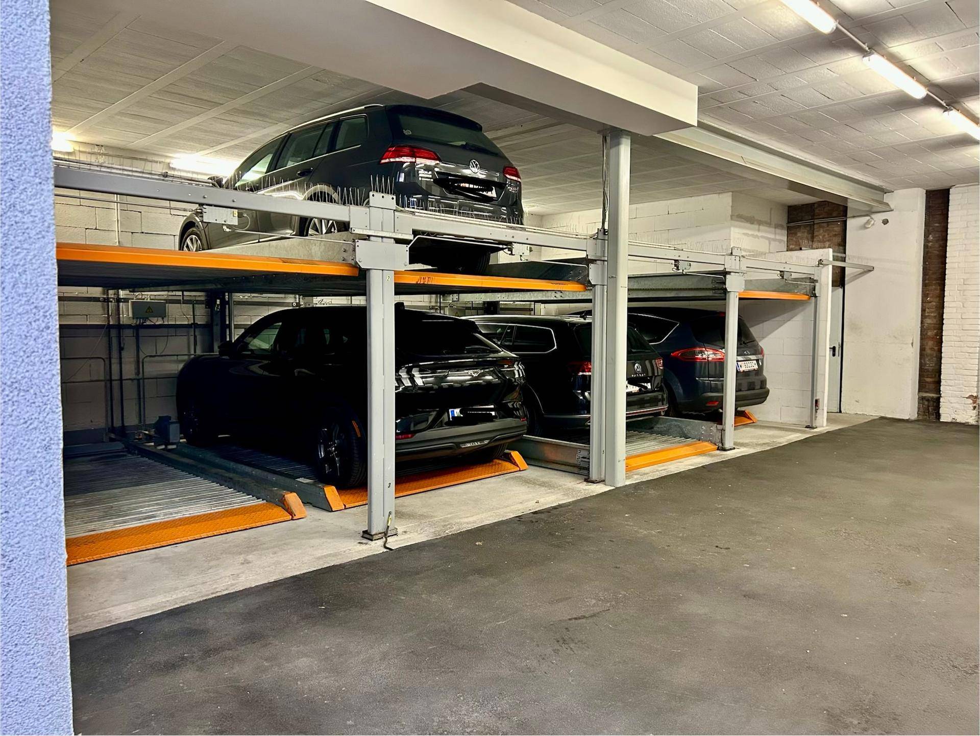 Mehrere Fahrzeuge parken in einem modernen, doppelstöckigen automatischen Parksystem einer Tiefgarage.