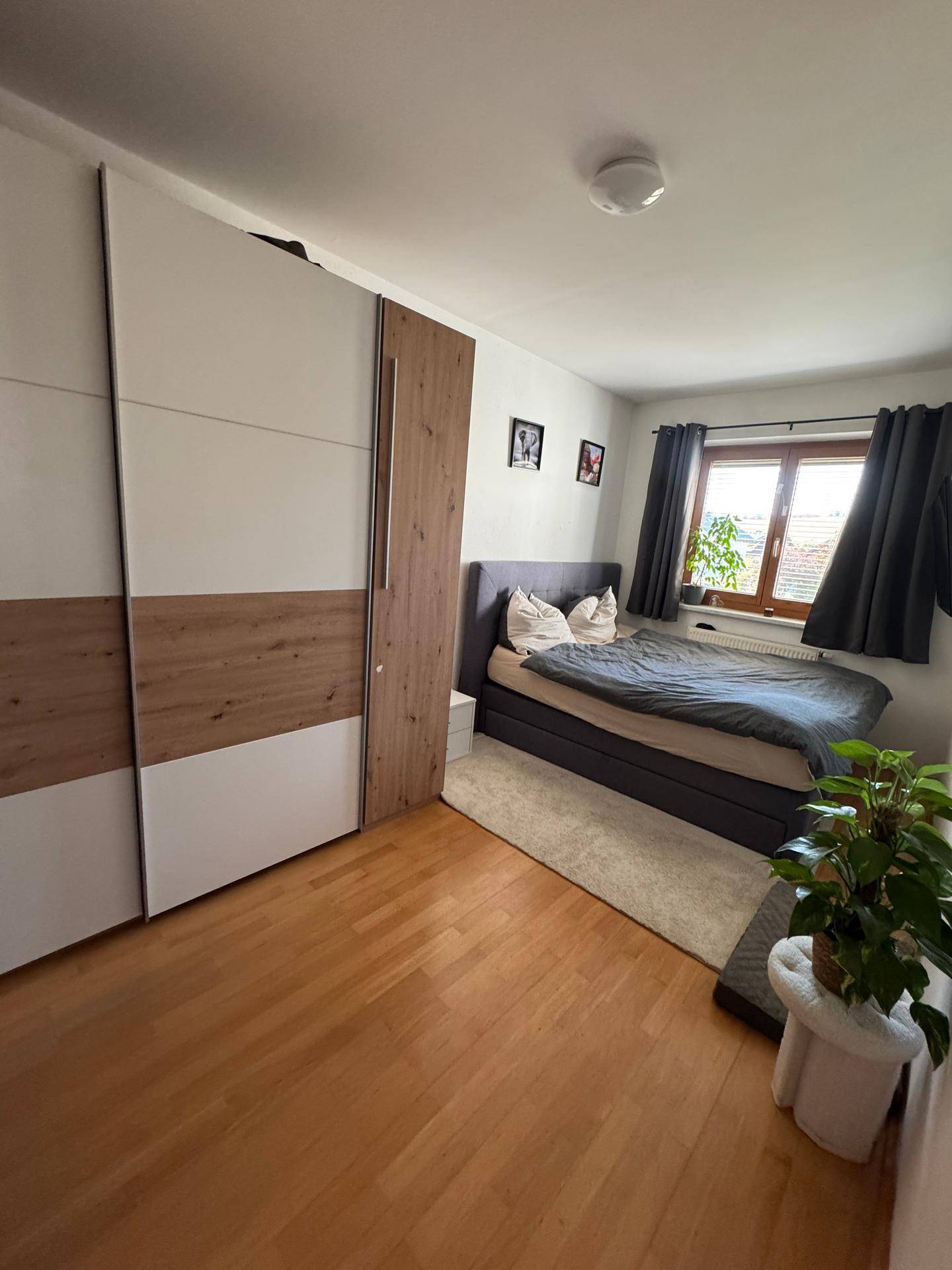 Schlafzimmer mit Doppelbett, großem Kleiderschrank und Holzboden, hell und funktional eingerichtet.