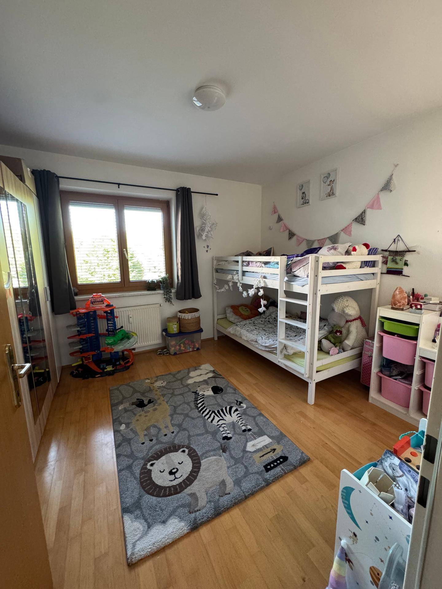 Kinderzimmer mit Etagenbett, Holzboden und spielerischer Dekoration, hell und freundlich.