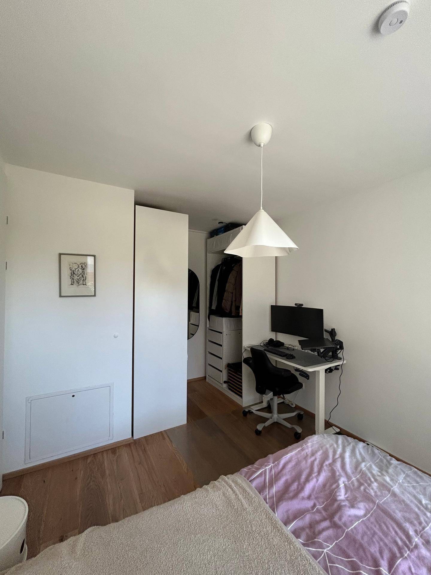 Schlafzimmer mit integrierten Kleiderschränken, Schreibtisch und hellem Holzboden.