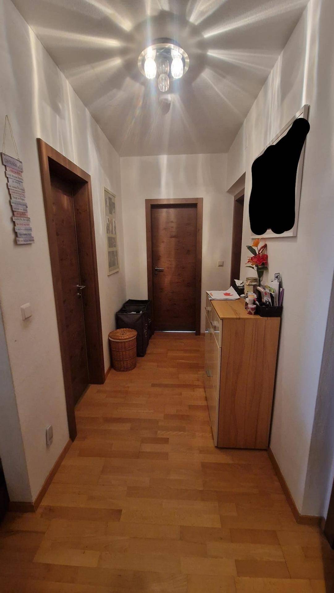 Heller Eingangsbereich mit Holzboden und Holzmöbeln, der zu den Zimmern führt.