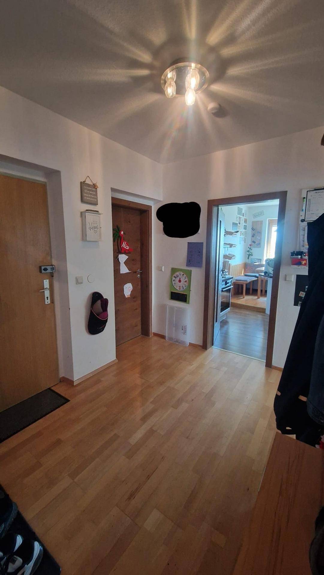 Heller Flur mit Holzboden und mehreren Türen, der verschiedene Räume verbindet.