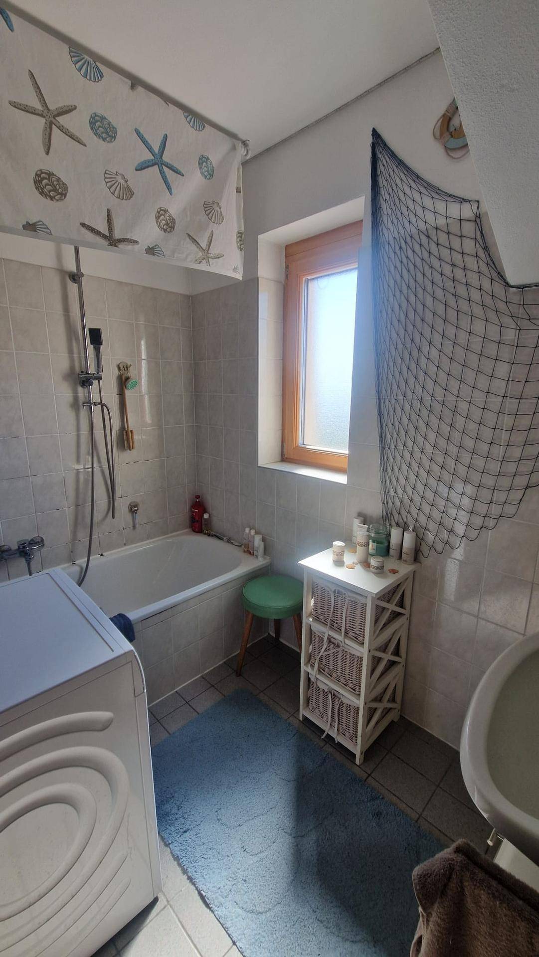 Badezimmer mit Badewanne, WC, Waschmaschine und Fenster für natürliche Belüftung.