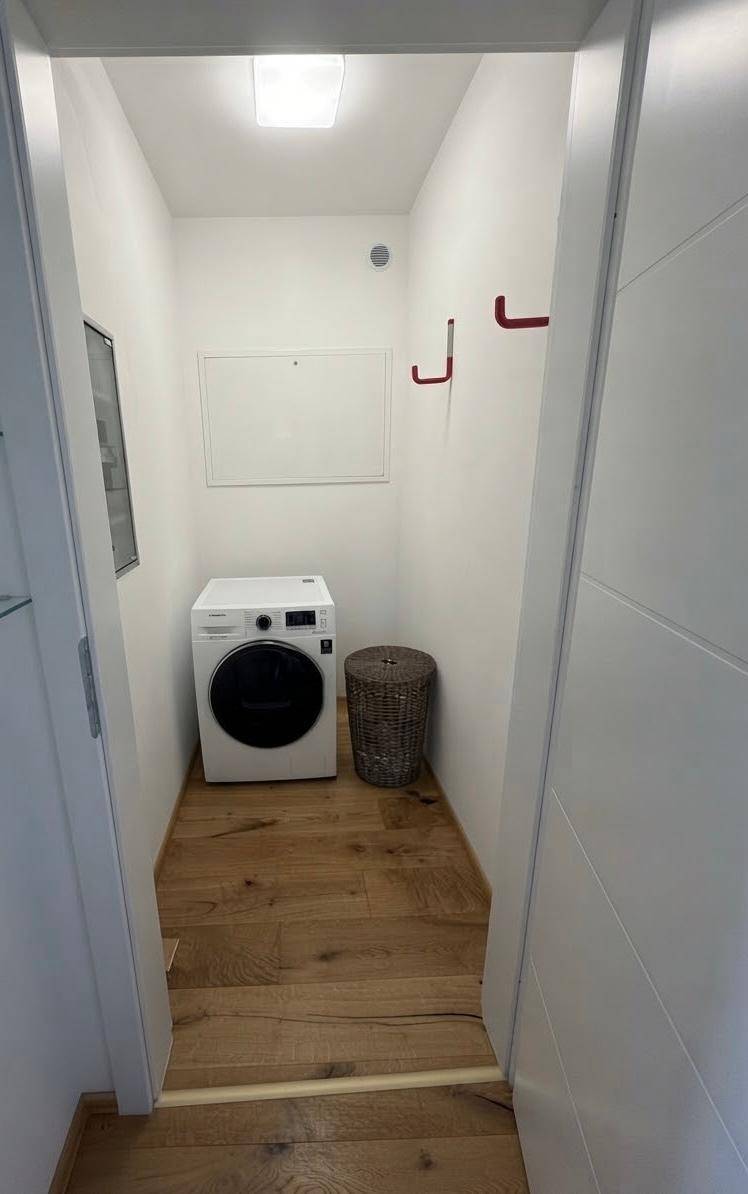 Praktischer Hauswirtschaftsraum mit Waschmaschine und Holzboden.