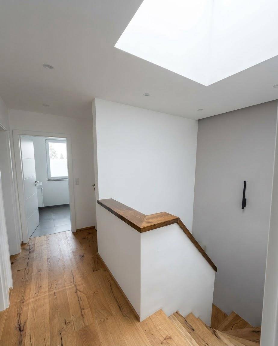 Heller Flur mit Holztreppe, Holzboden und Oberlicht für natürliches Licht.