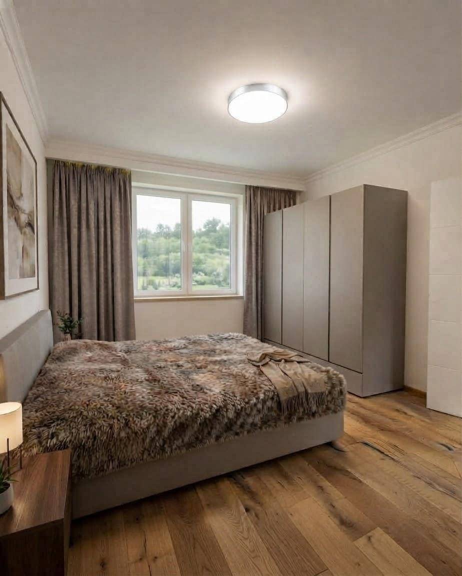 Gemütliches Schlafzimmer mit Holzboden, großem Bett und Blick ins Grüne.