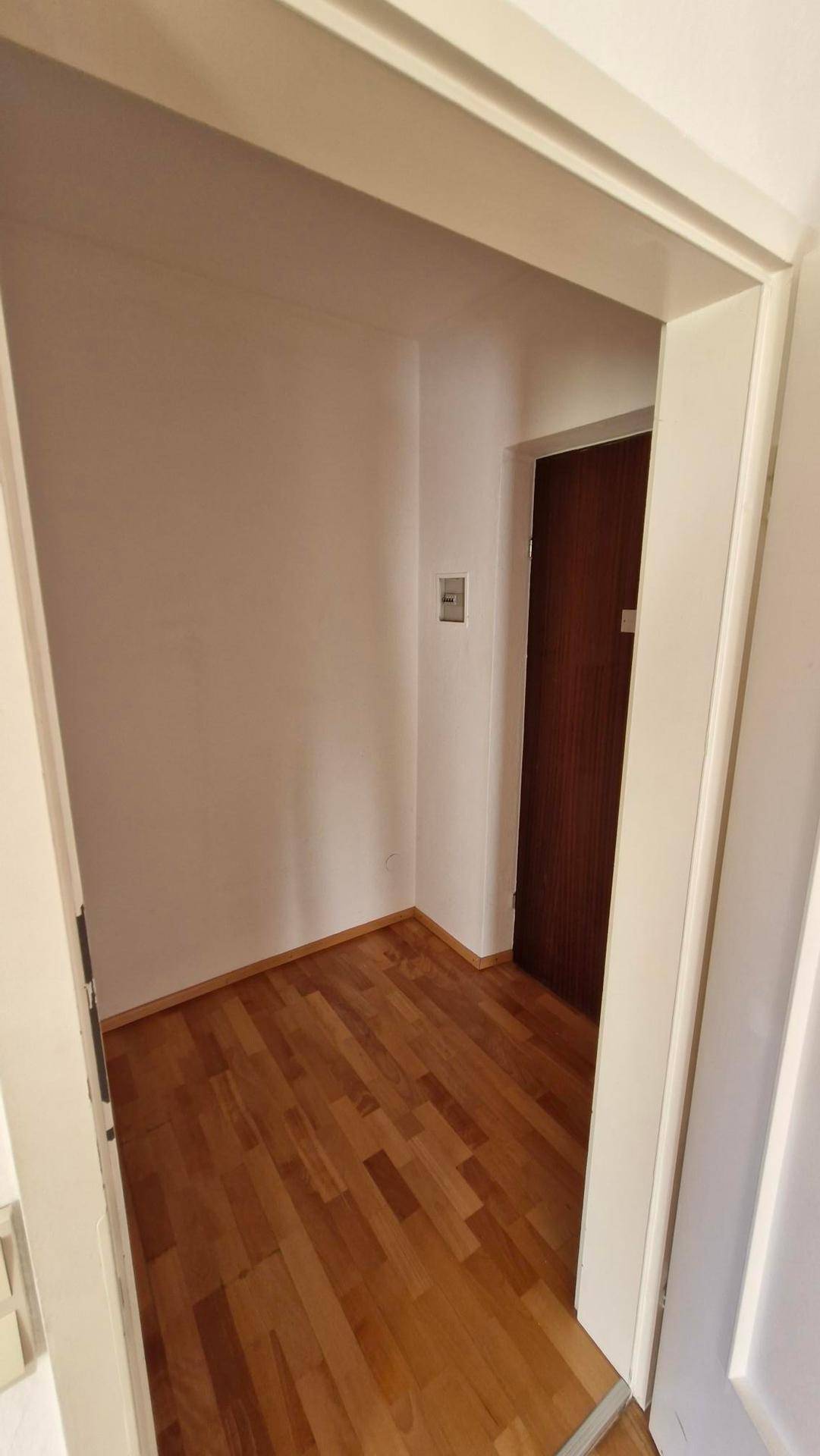 Kleiner Flur oder Abstellraum mit Parkettboden und einer weiteren Tür.