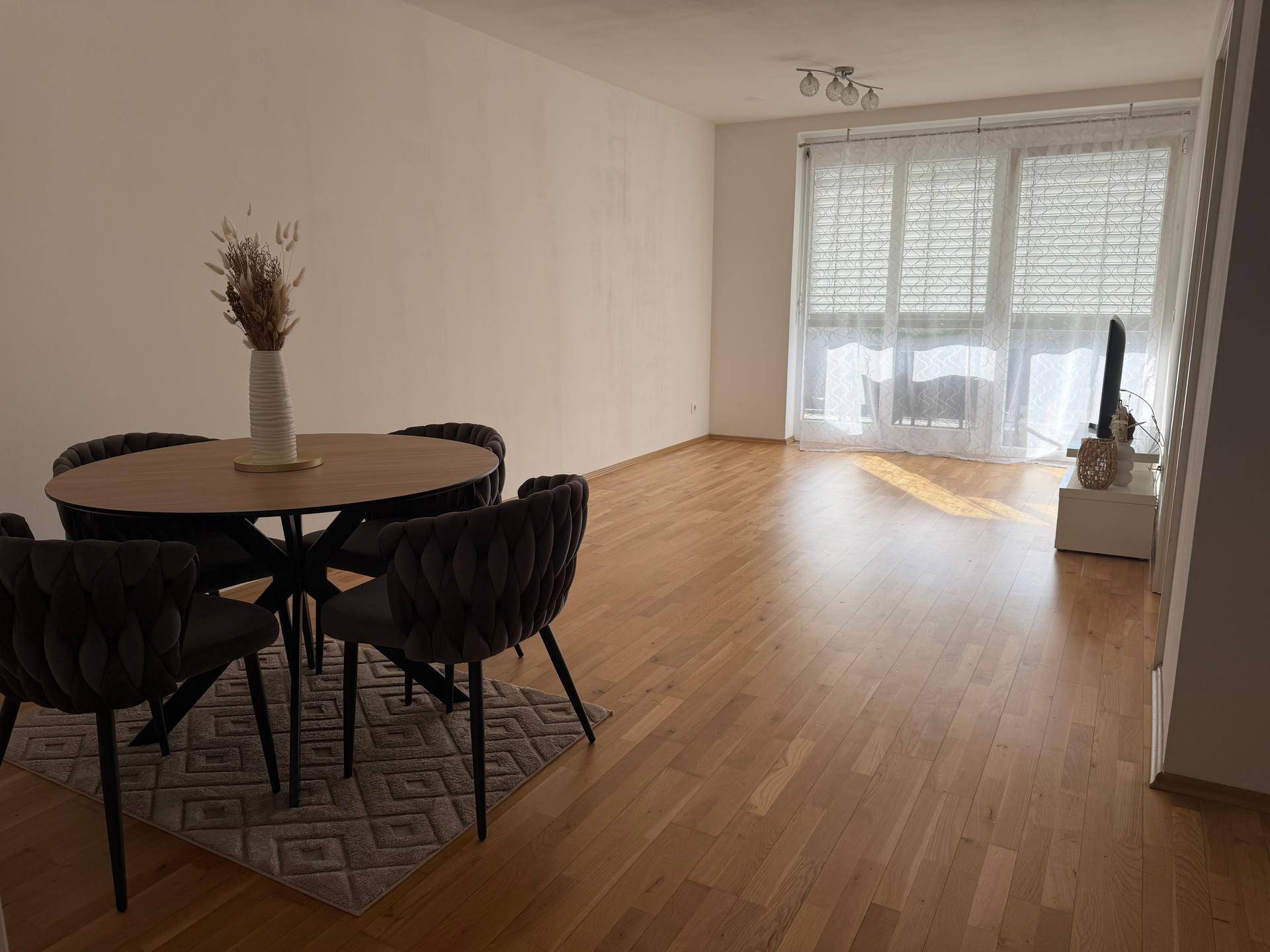 Geräumiger Wohn-Essbereich mit Parkettboden und modernem Esstisch, hell durch große Fenster.
