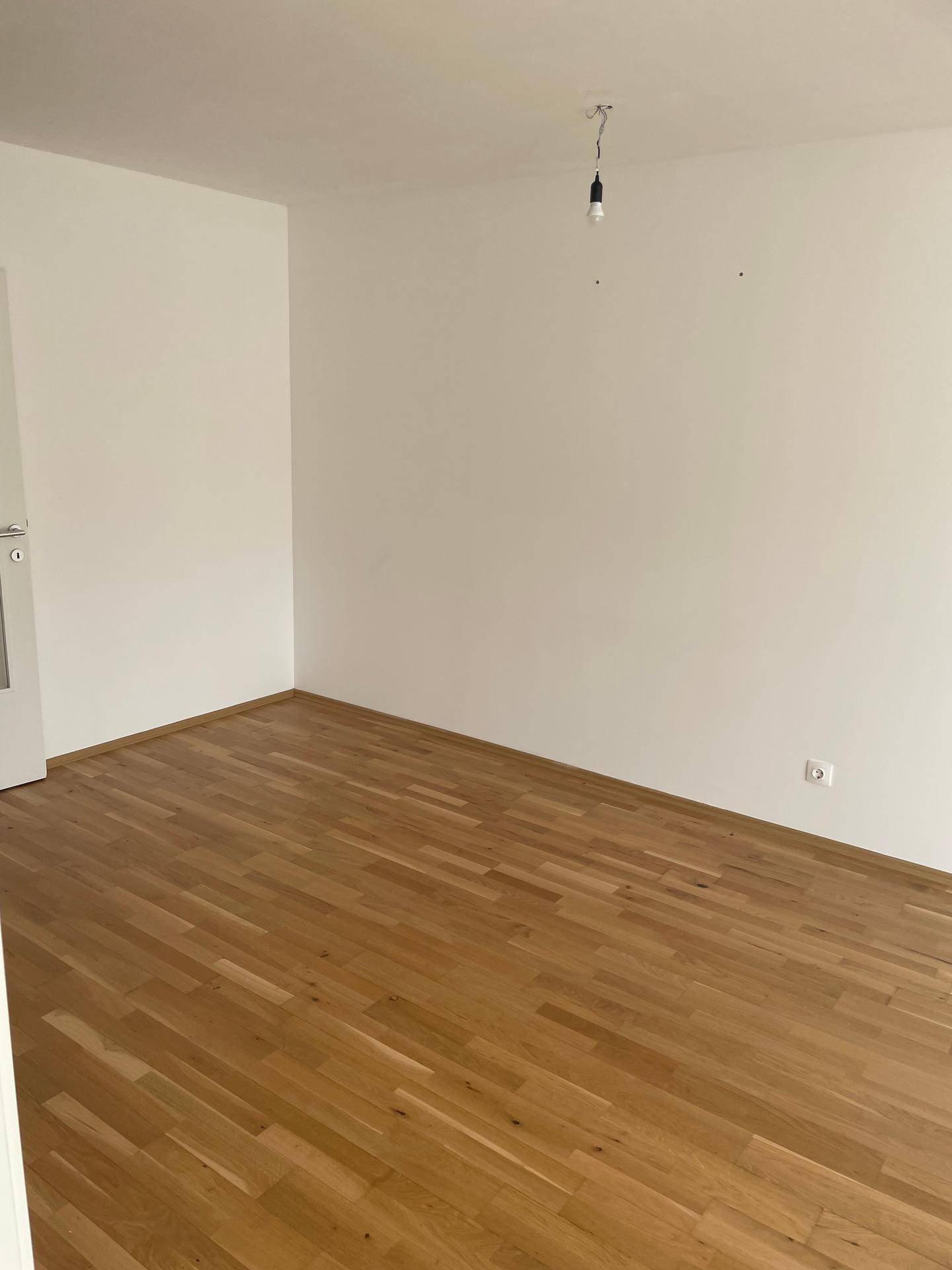 Leeres Schlafzimmer mit hellem Parkettboden und weißen Wänden, bereit für die individuelle Einrichtung.