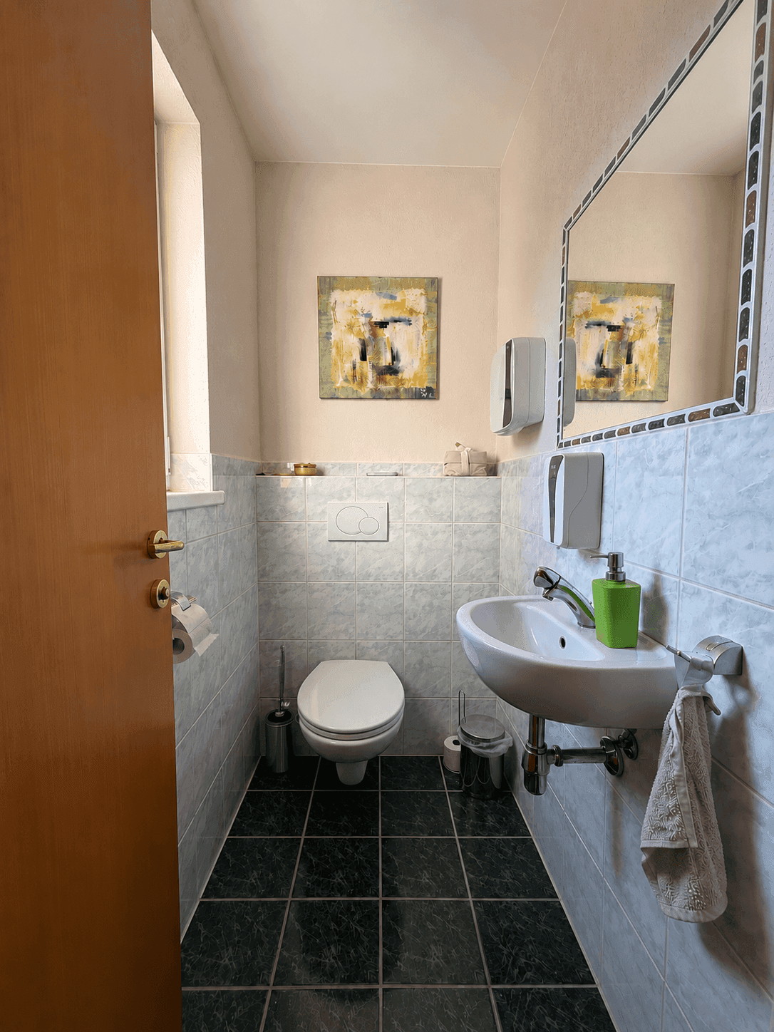 Gäste-WC mit Fenster, Waschbecken und Wand-WC.