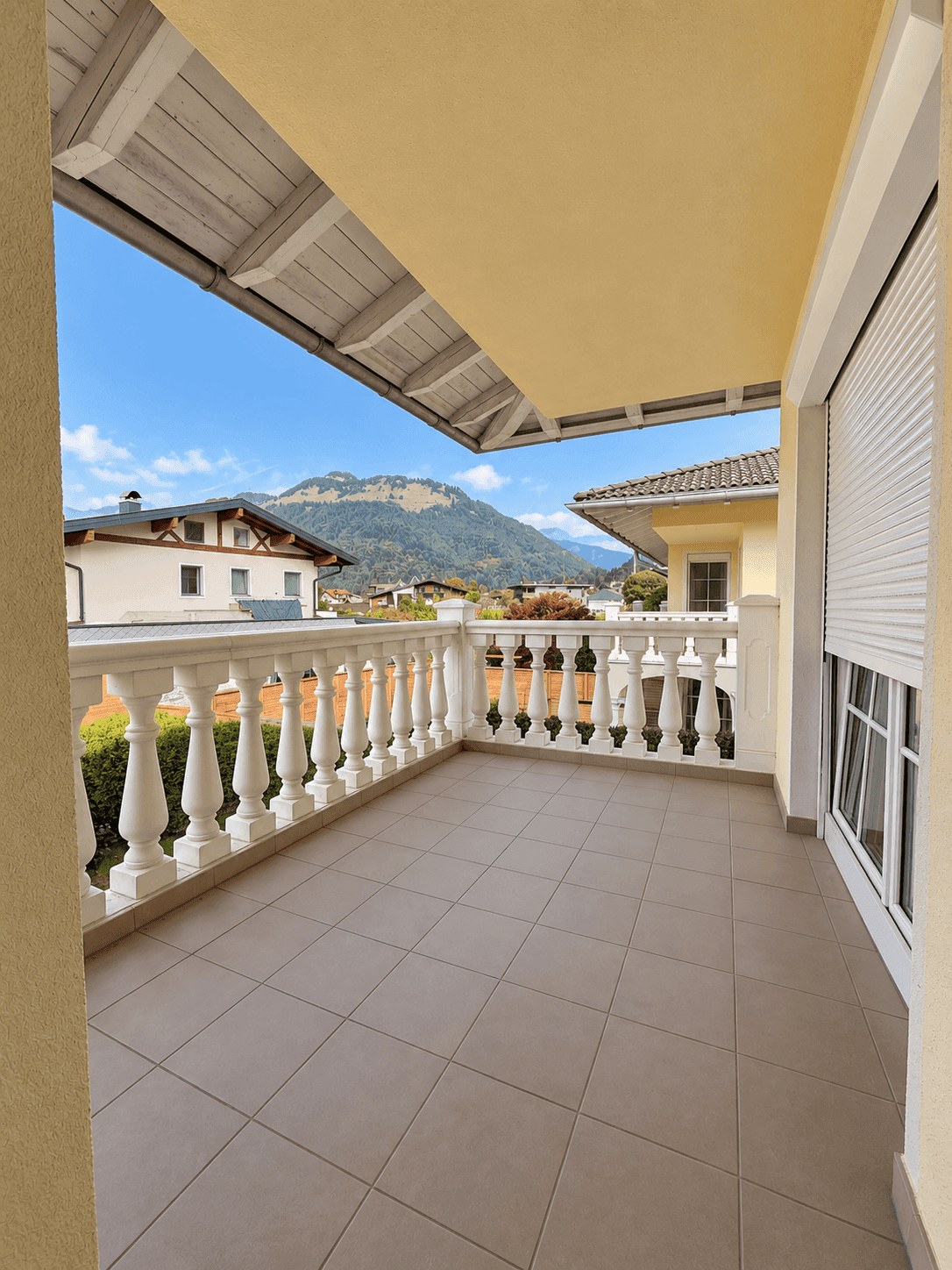Geräumiger Balkon mit Fliesenboden, Balustrade und herrlichem Bergblick.