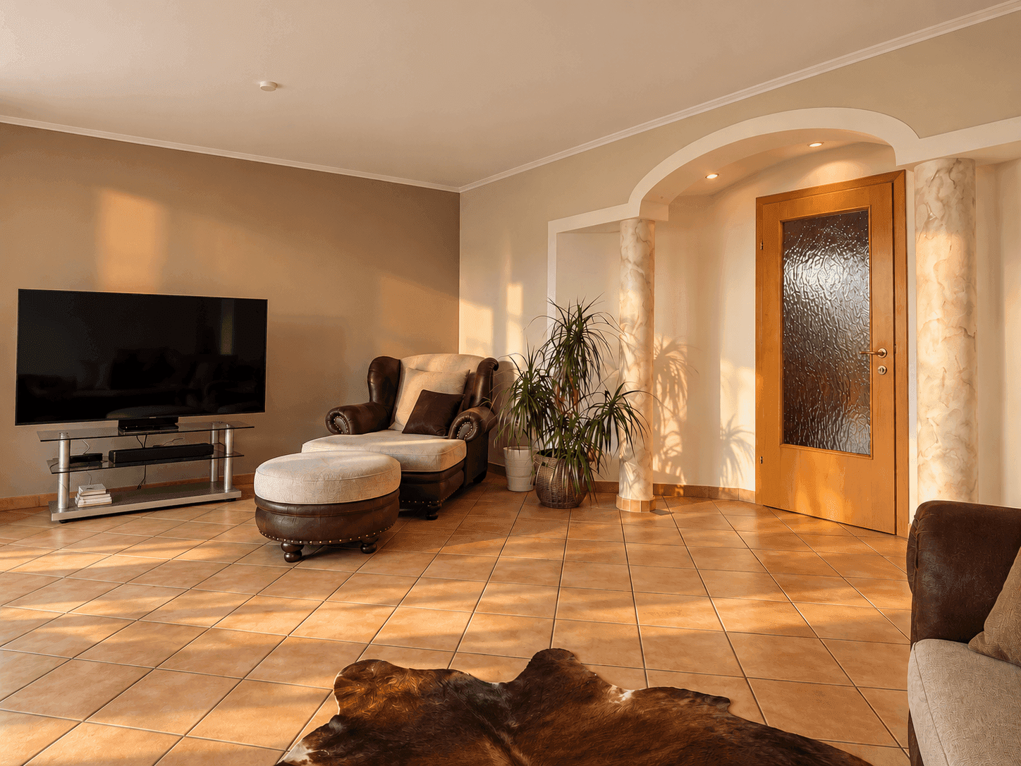 Helles Wohnzimmer mit Fliesenboden, gemütlichem Sessel und viel natürlichem Lichteinfall.