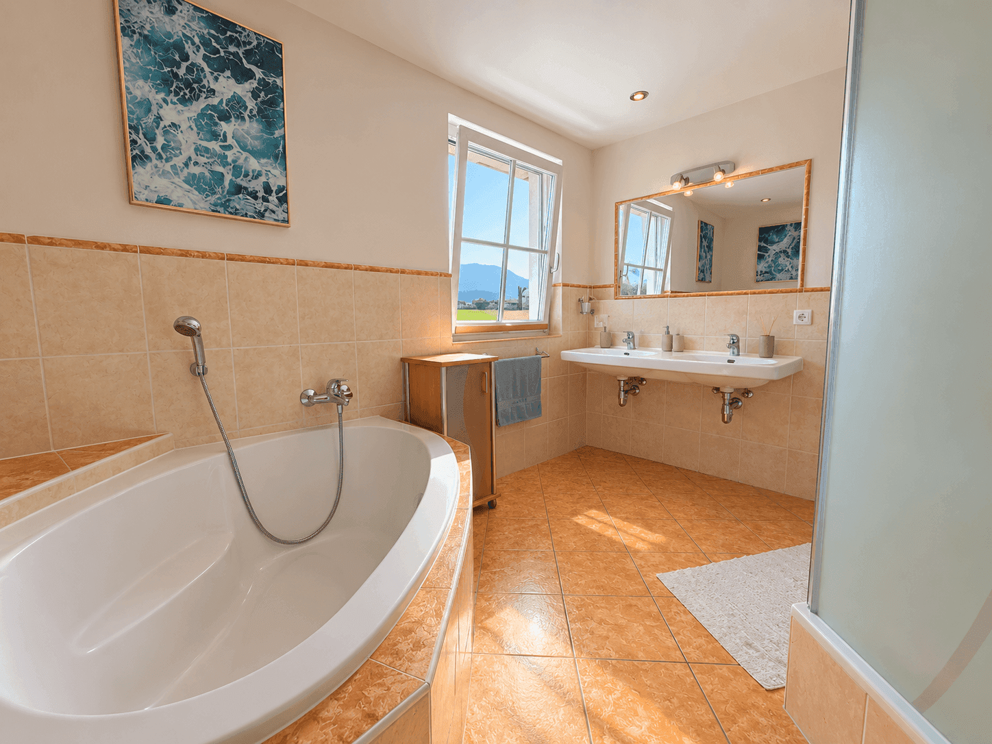 Geräumiges Badezimmer mit Eckbadewanne, Doppelwaschbecken und Fenster mit Bergblick.