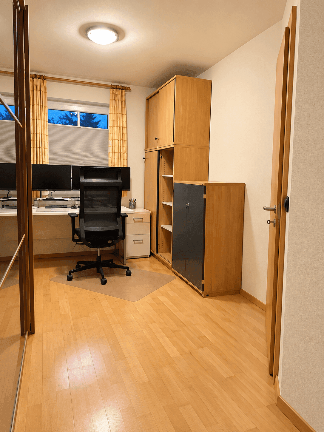 Funktionales Arbeitszimmer mit Holzboden, Schreibtisch und Stauraum.