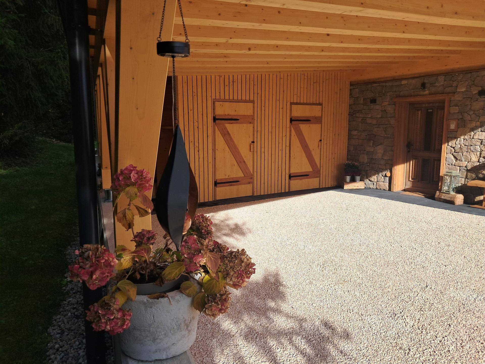 Carport-Einfahrt mit Holzwänden und einer dekorativen Pflanze im Vordergrund.
