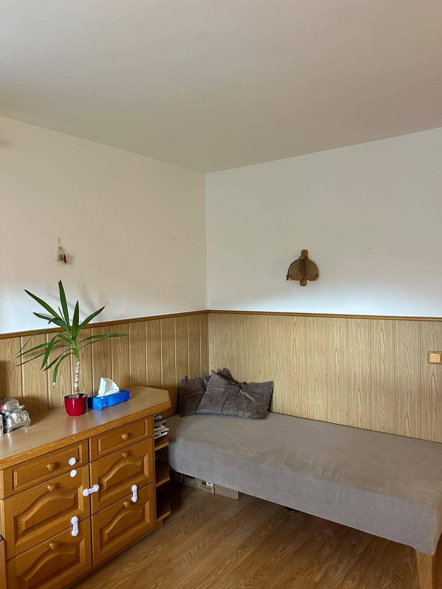 Gemütliches Schlafzimmer mit Holzvertäfelung, Einzelbett und einem rustikalen Holzschrank.