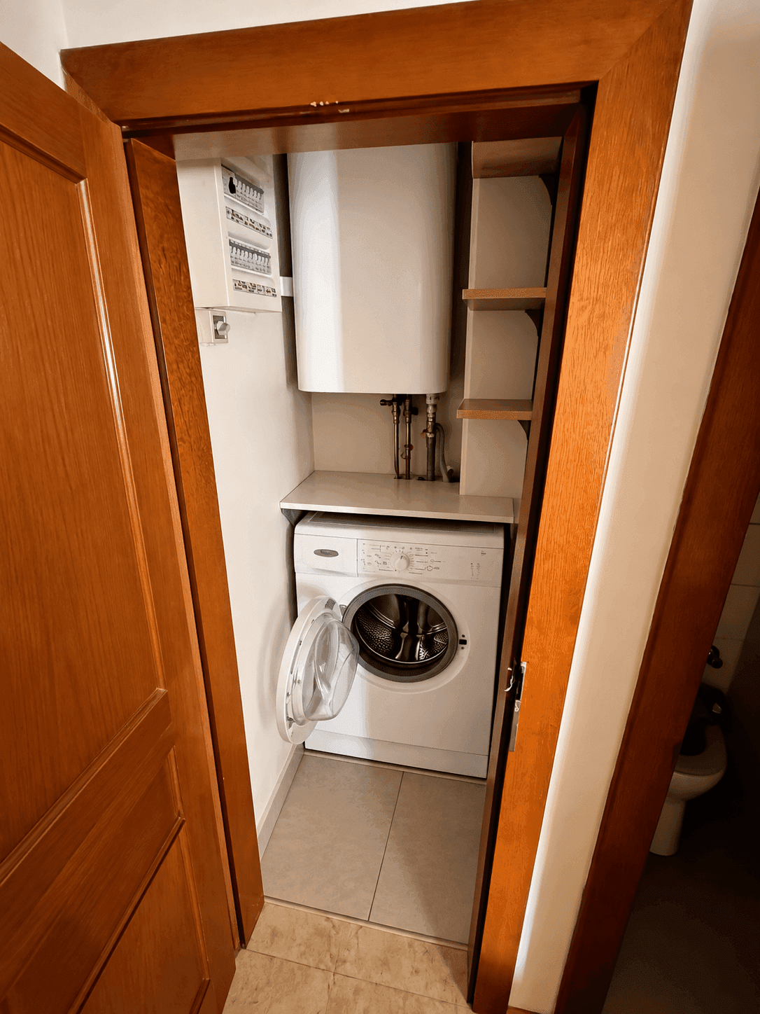 Praktischer Hauswirtschaftsraum mit Waschmaschine und Warmwasserboiler, bietet zusätzlichen Stauraum.