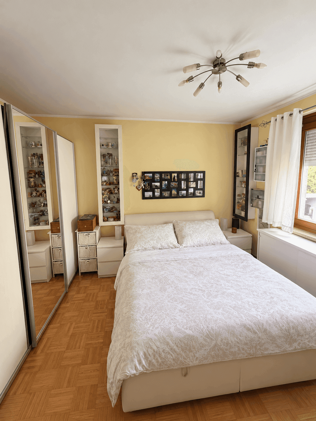 Helles Schlafzimmer mit Doppelbett, Spiegelschrank und Parkettboden, freundlich und funktional eingerichtet.