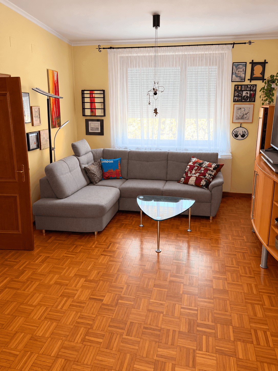 Gemütliches Wohnzimmer mit L-förmigem Sofa, Couchtisch und hellem Parkettboden, einladend gestaltet.