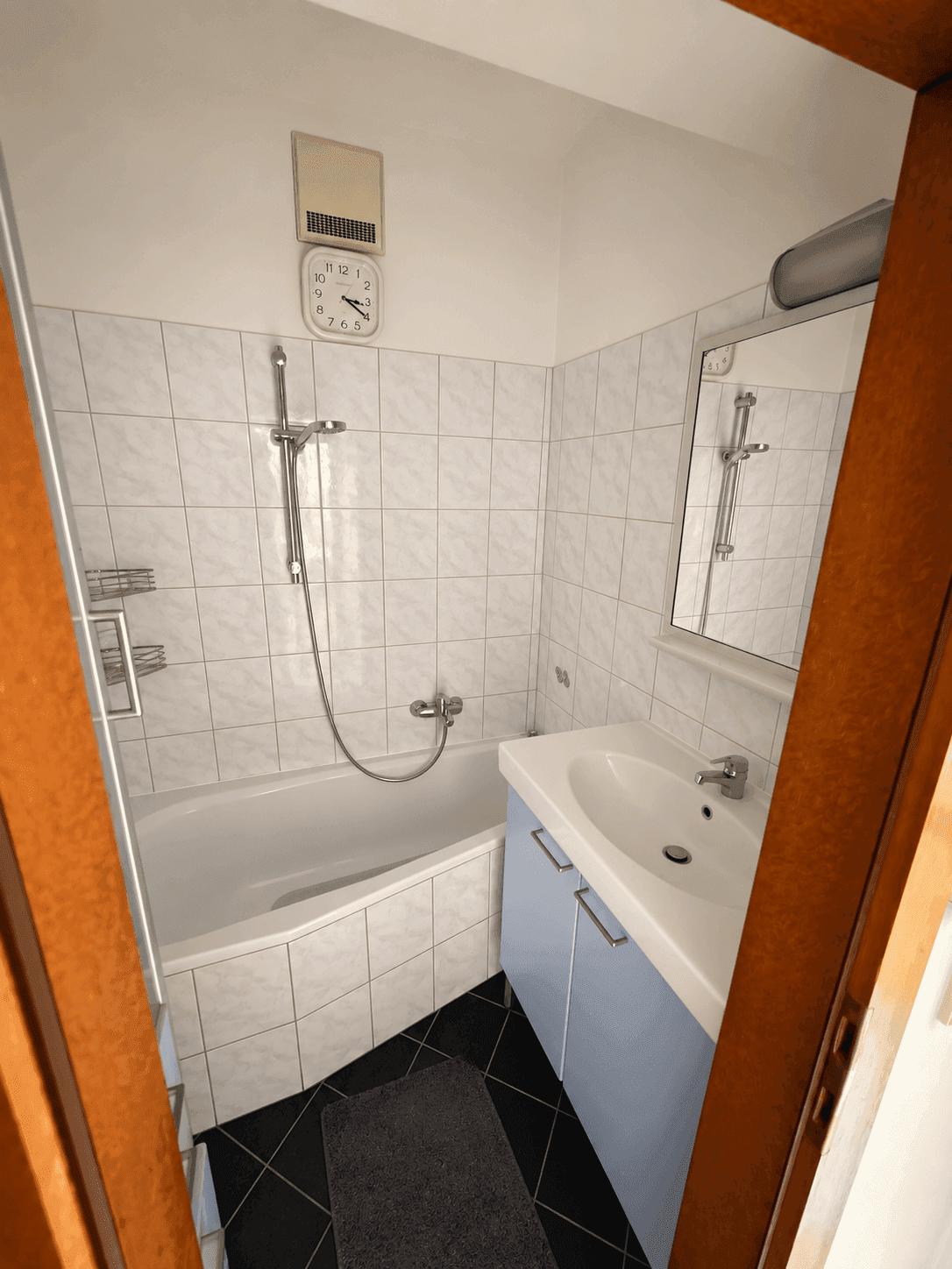 Funktionales Badezimmer mit Badewanne, integrierter Dusche und Waschbecken, hell gefliest und sauber.