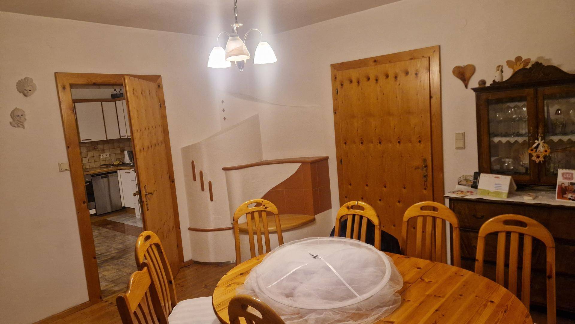 Esszimmer mit rustikalem Holztisch, Holzstühlen und Holztüren, die zur Küche führen.