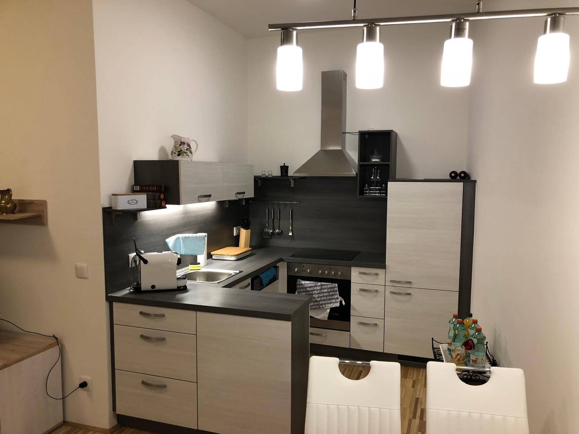 Moderne Einbauküche mit dunklen Arbeitsplatten, Dunstabzugshaube und Essbereich.