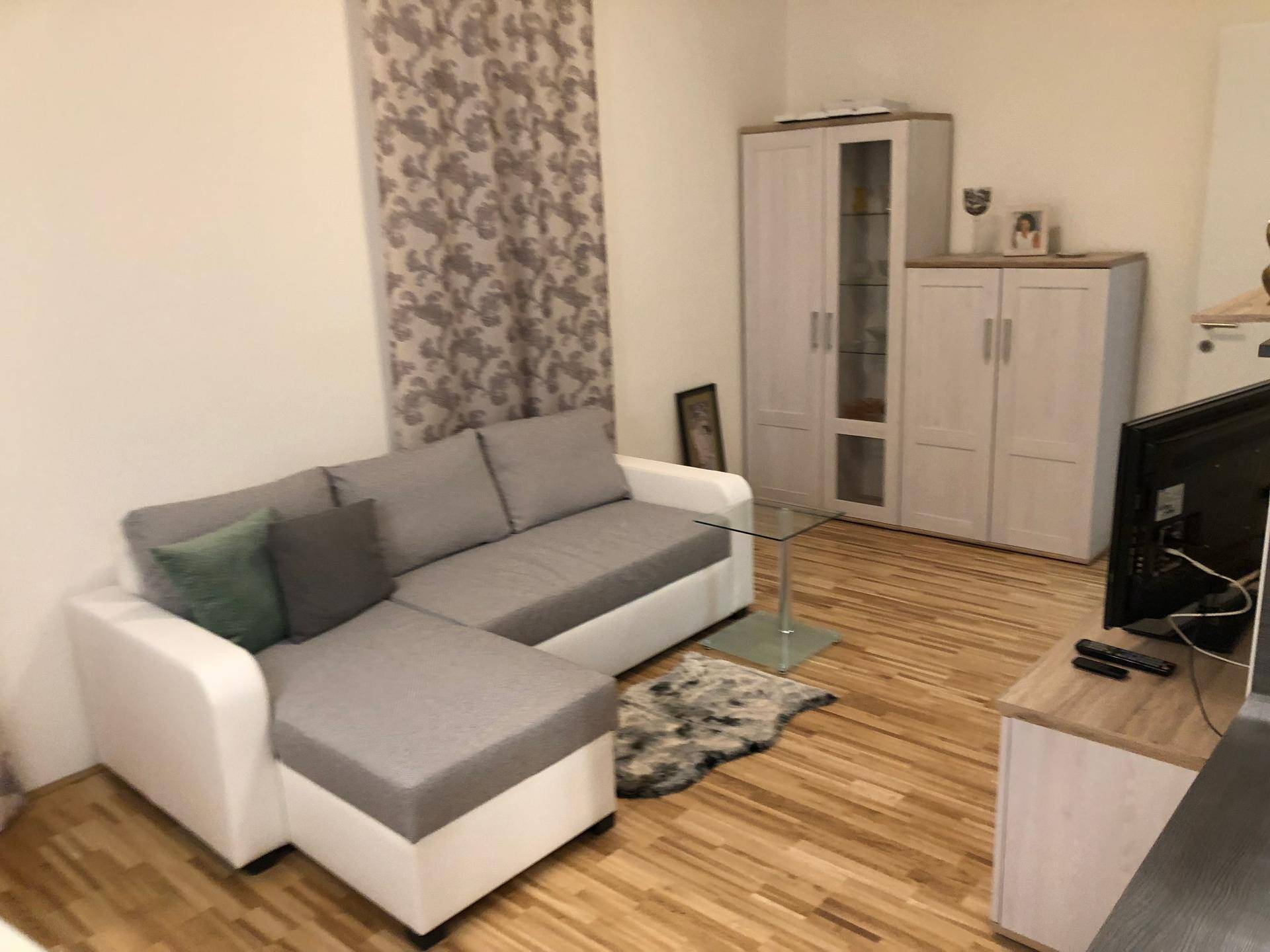 Gemütliches Wohnzimmer mit Ecksofa, Holzboden und modernem Dekor.