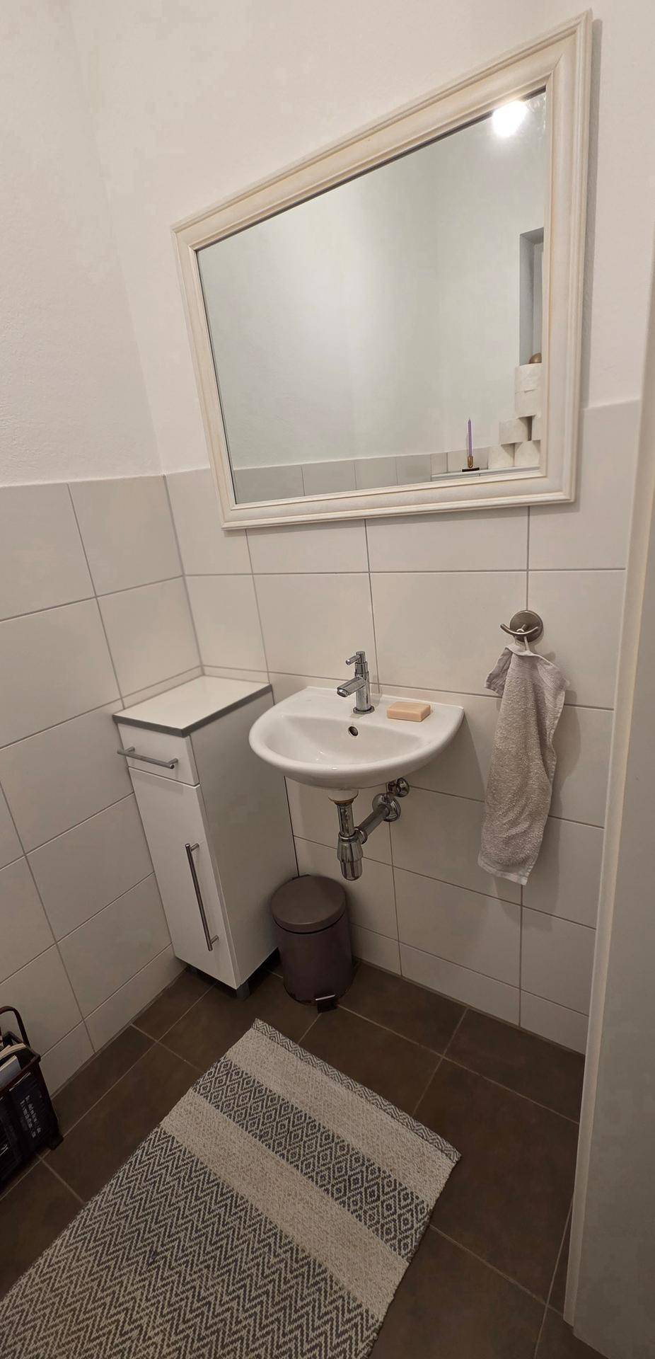 Gäste-WC mit modernem Waschbecken, Spiegel und praktischem Unterschrank.
