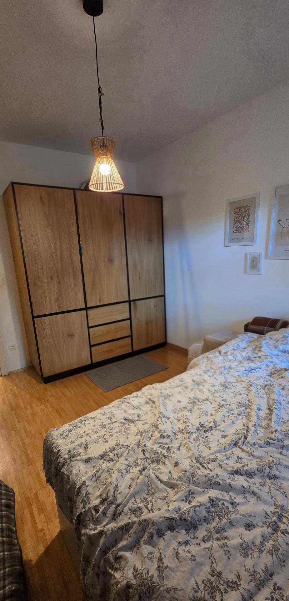 Schlafzimmer mit großem Bett und einem geräumigen Holzschrank.