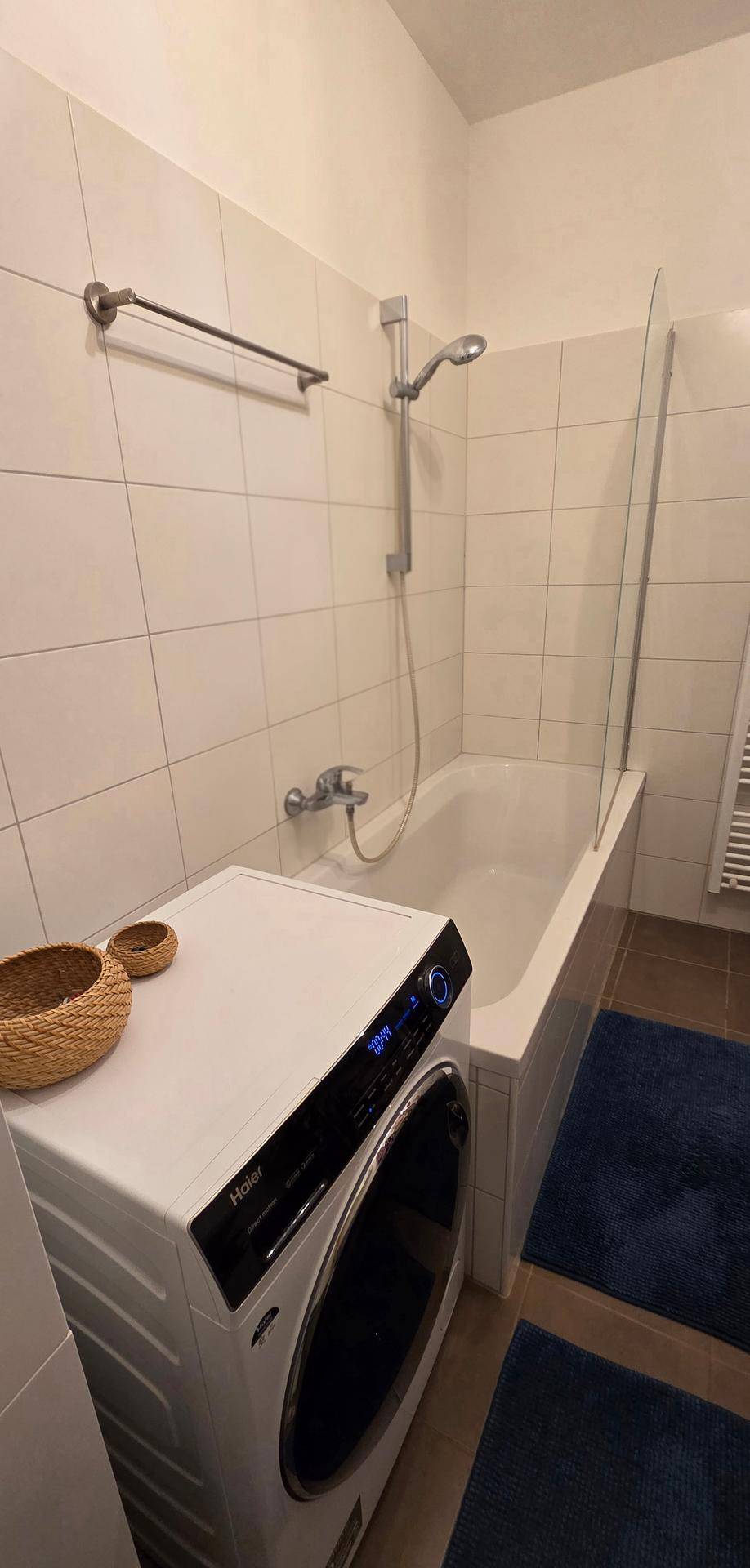 Badezimmer mit Badewanne und integrierter Waschmaschine.