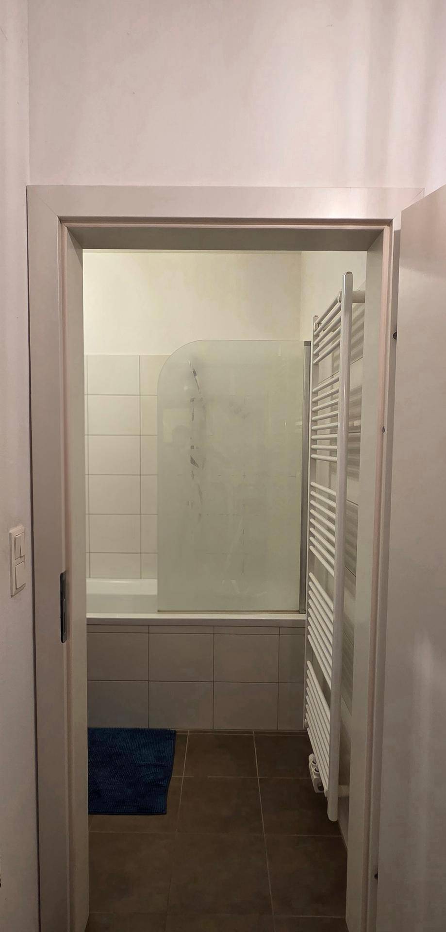 Blick durch die Tür in ein Badezimmer mit Badewanne und Handtuchheizkörper.