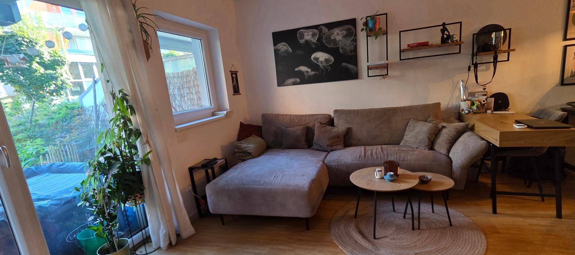 Wohnzimmer mit bequemer Couch, Holzboden und direktem Zugang zum Außenbereich.