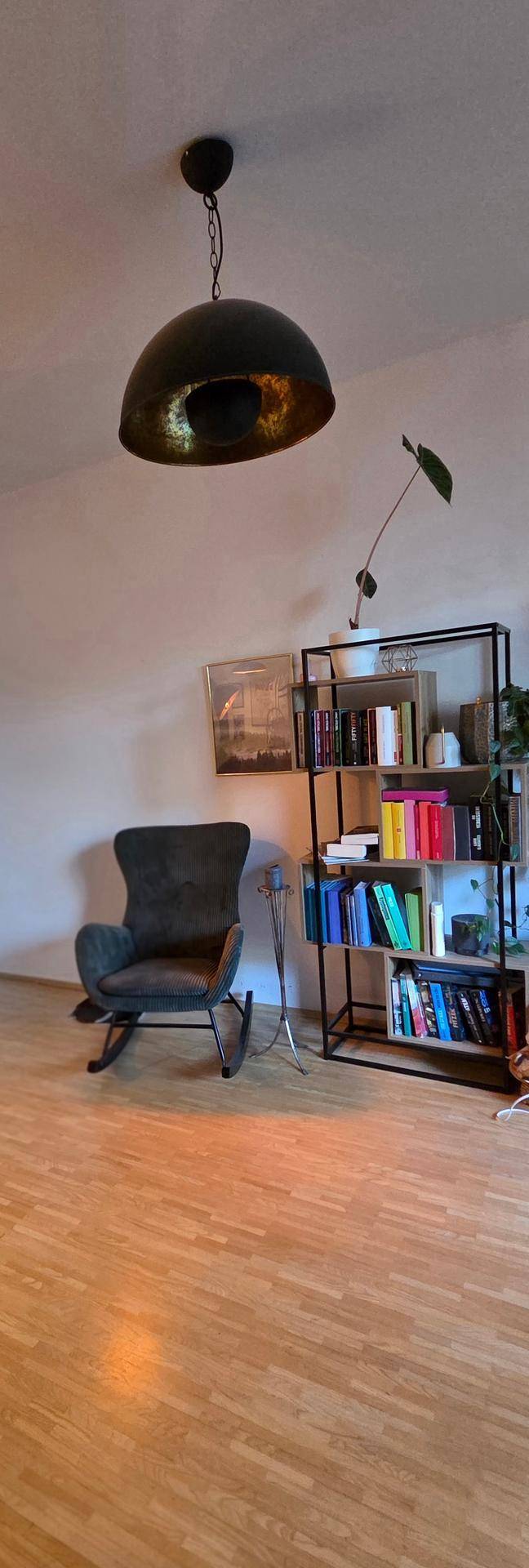 Gemütliche Leseecke im Wohnzimmer mit Schaukelstuhl und Bücherregal.