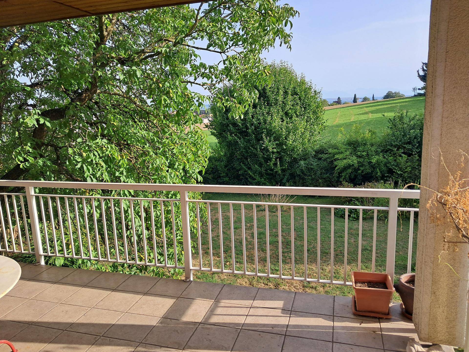 Blick von einem gefliesten Balkon auf eine grüne Wiese und die umliegende Landschaft.