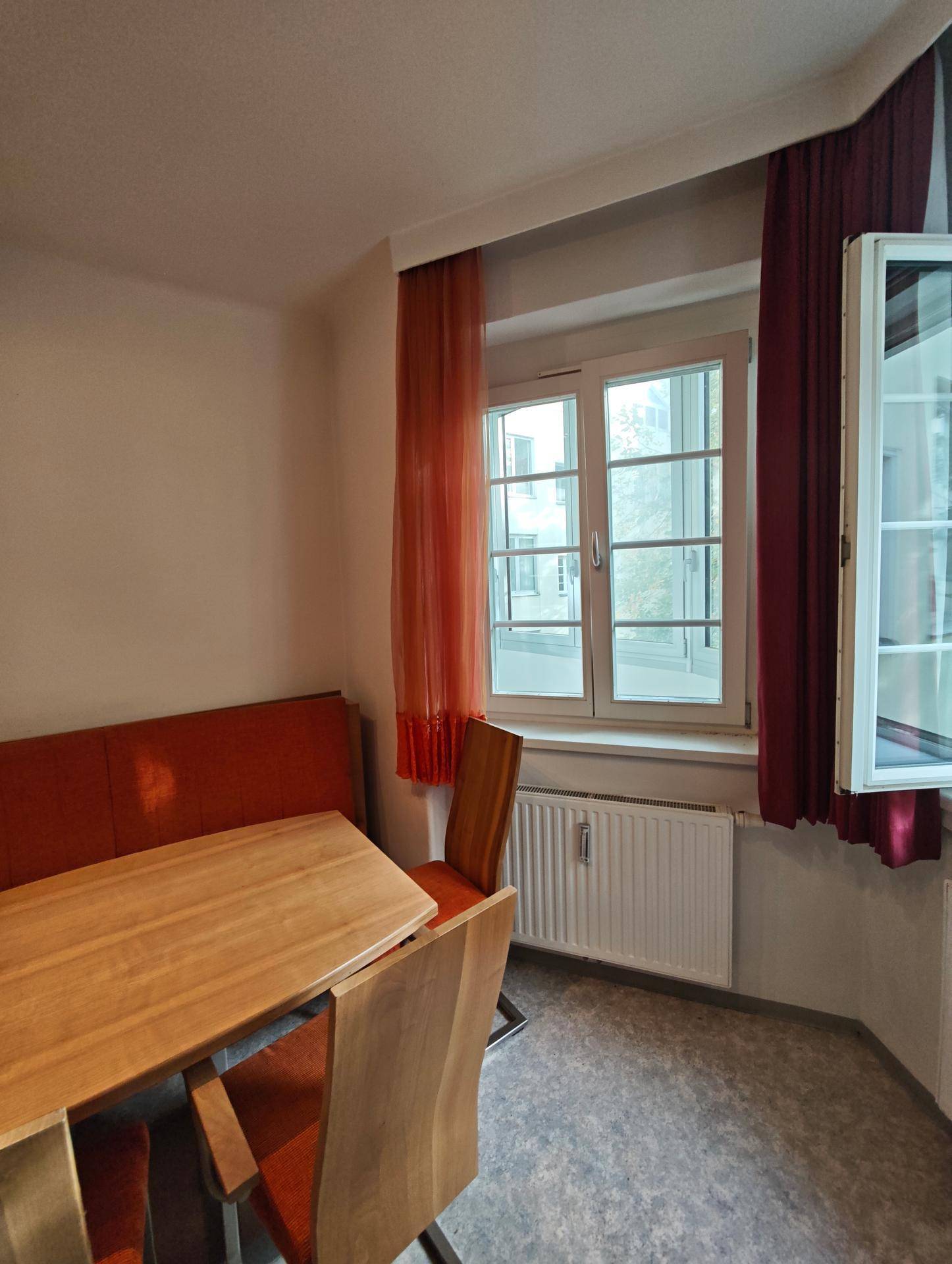 Essbereich der Küche mit Fenster, Heizkörper und Blick auf die Umgebung.