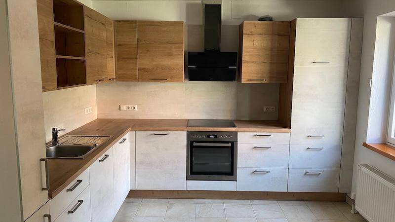 Detailansicht der modernen Küche mit Holz- und hellen Fronten, Spüle und Dunstabzugshaube.