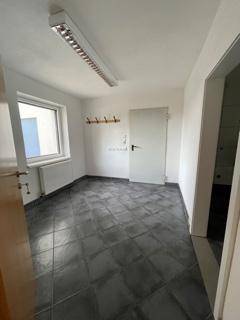 Funktionaler Raum mit dunklen Fliesen, Fenster und Garderobenhaken an der Wand.