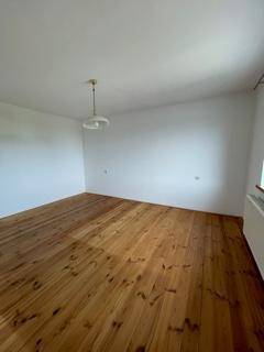 Heller, leerer Raum mit Holzdielenboden und weiß gestrichenen Wänden, bereit zur Gestaltung.