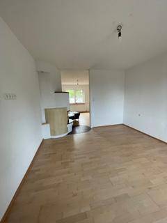 Geräumiges Wohnzimmer mit hellem Parkettboden und einem modernen Kaminofen.