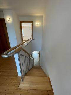 Holztreppe mit modernem Metallgeländer, die in das obere Stockwerk führt.
