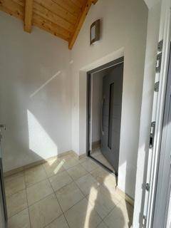Heller Eingangsbereich mit Fliesenboden und Holzdecke, der zum Inneren des Hauses führt.