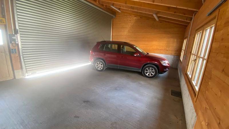 Geräumige Garage mit Rolltor und Holzverkleidung, bietet Platz für ein Fahrzeug.