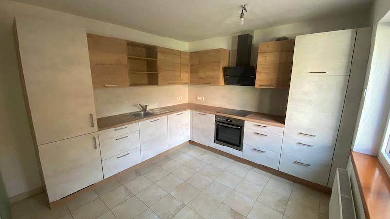 Moderne Einbauküche mit hellen Holzfronten, Induktionskochfeld und integriertem Backofen.