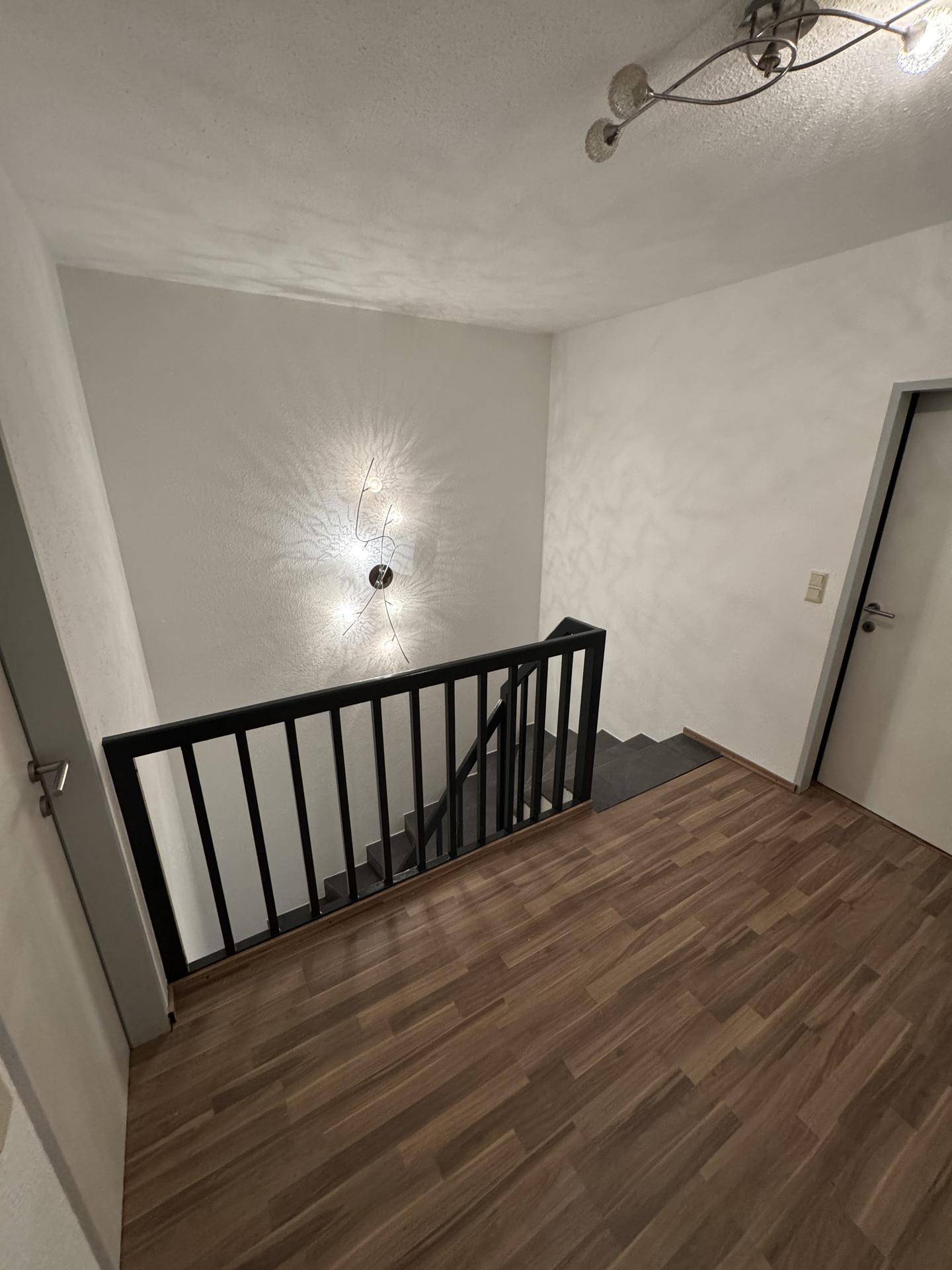 Heller Flur im Obergeschoss mit Laminatboden und Blick auf das Treppenhaus, gut beleuchtet.