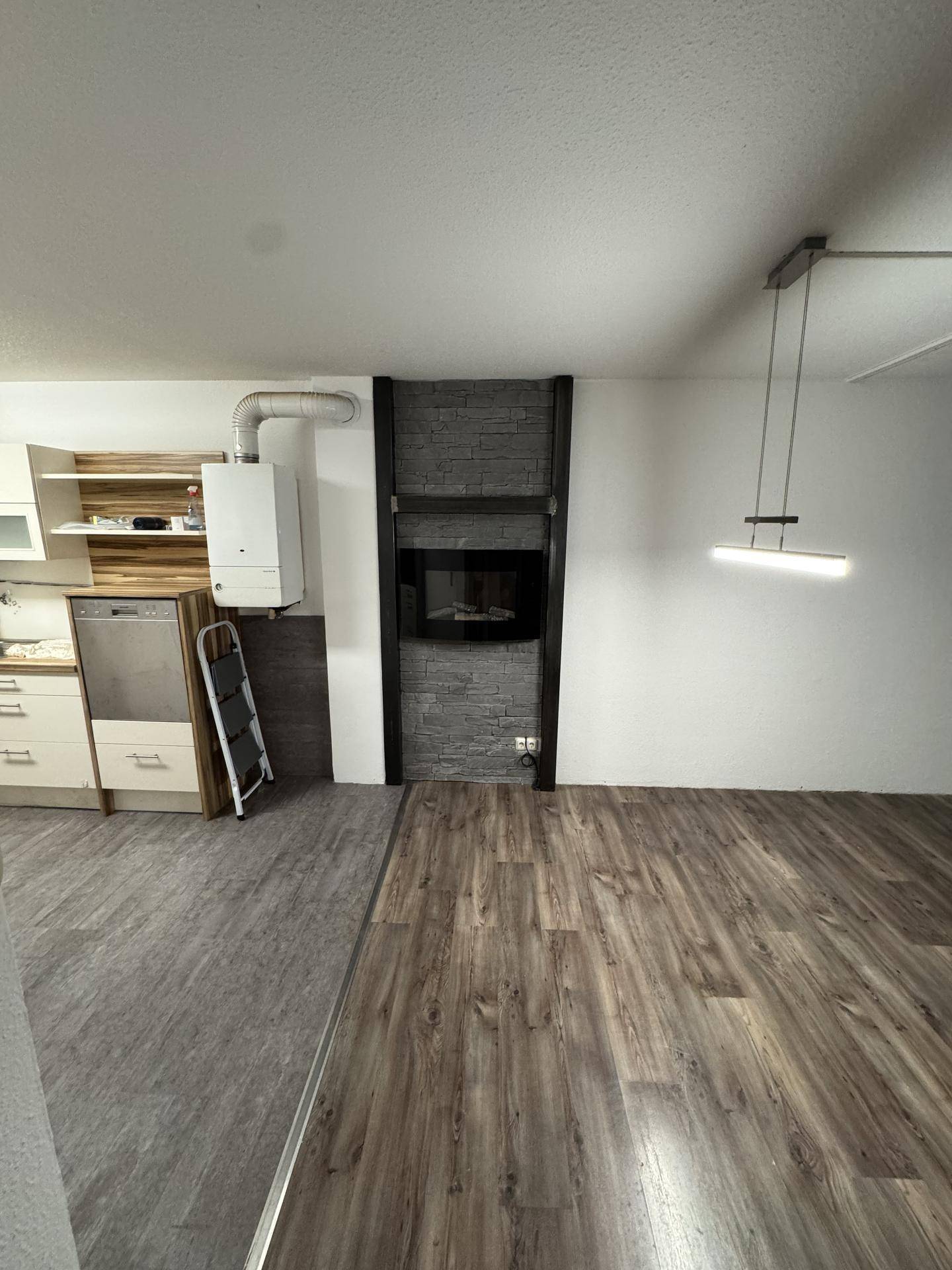 Küchenbereich mit Laminatboden, Heizung und einem modernen Kamin als stilvoller Blickfang.