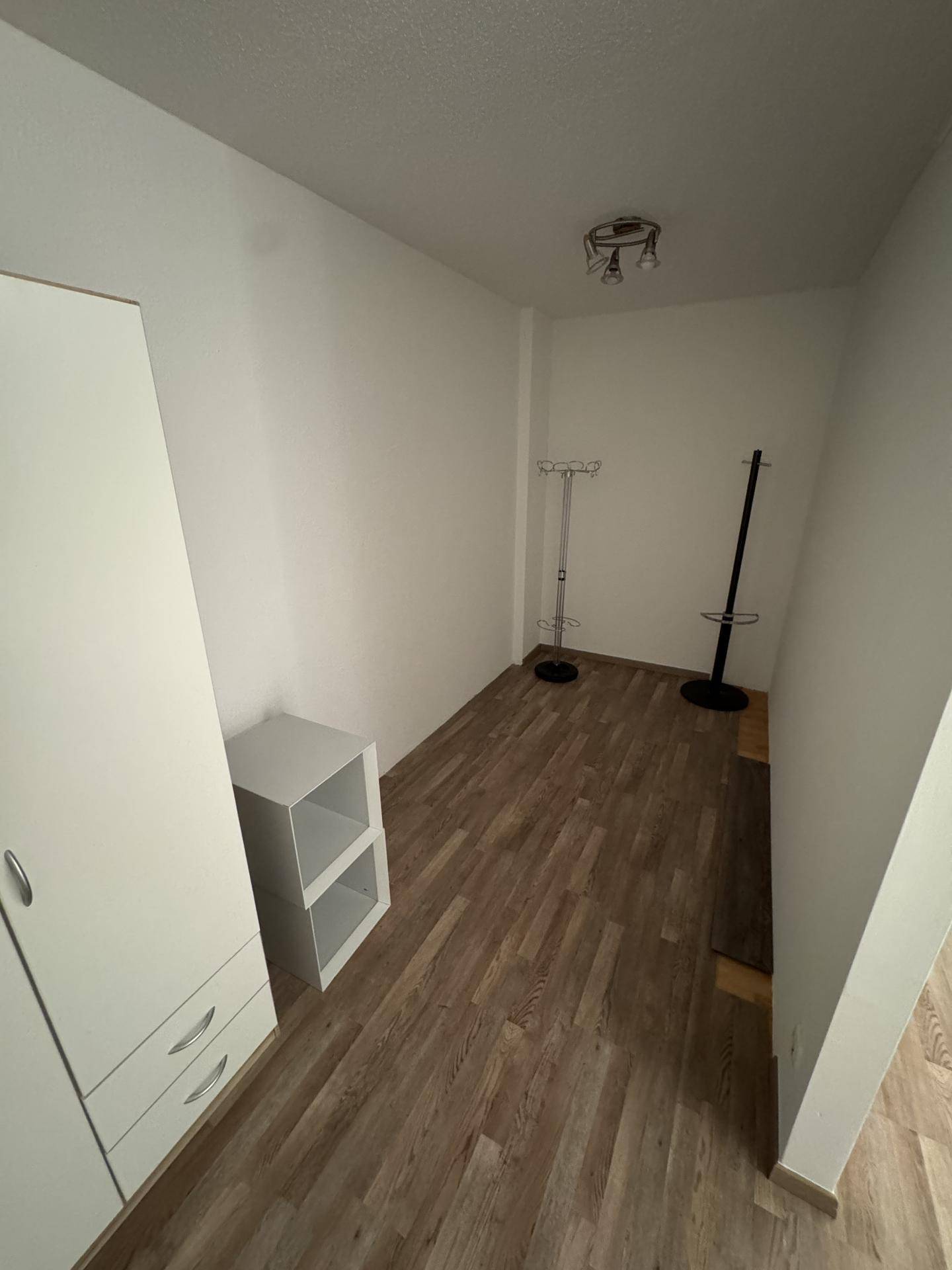 Kleiner Raum mit Laminatboden und weiß gestrichenen Wänden, ideal als Ankleidezimmer oder Abstellraum.