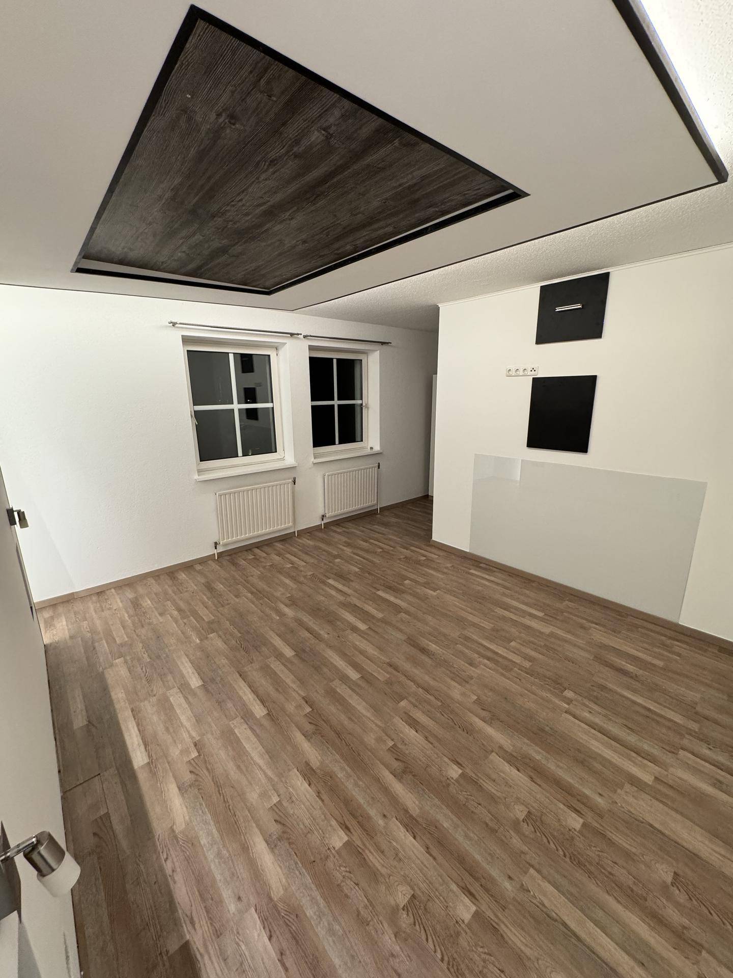 Helles Schlafzimmer mit zwei Fenstern, Laminatboden und moderner Deckenbeleuchtung für angenehmes Ambiente.
