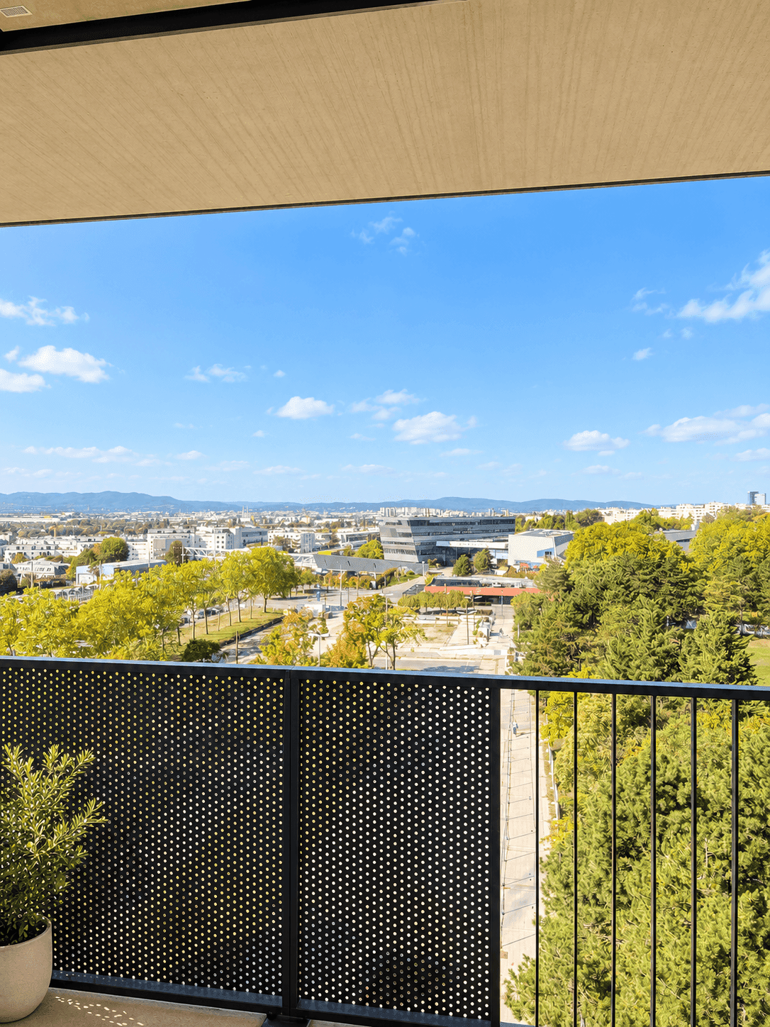 Weitläufiger Stadtblick von einem Balkon mit moderner Brüstung und grüner Umgebung.