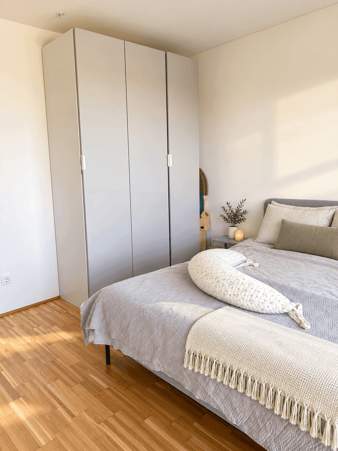 Gemütliches Schlafzimmer mit Holzboden und einem großen, modernen Kleiderschrank in hellem Grau.