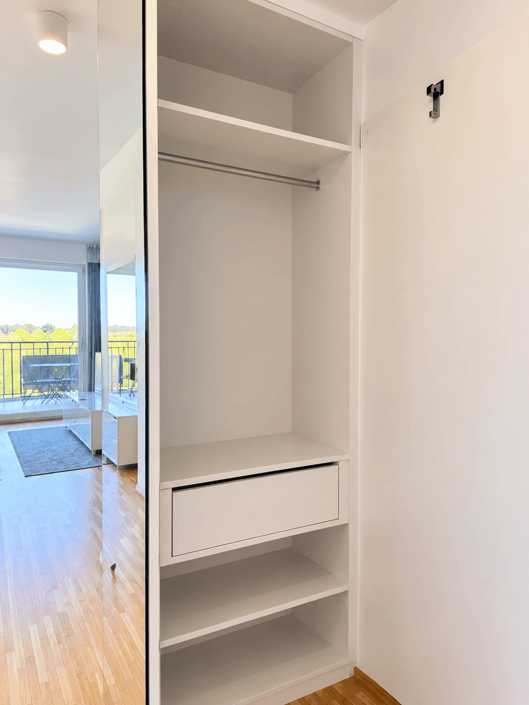 Offener Einbauschrank im Flur mit Regalen und Kleiderstange für zusätzlichen Stauraum.